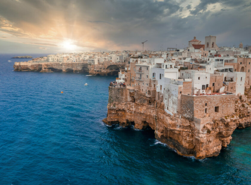 Cityscape of Polignano a Mare surrounded by the sea under the sunlight and a cloudy sky in Italy