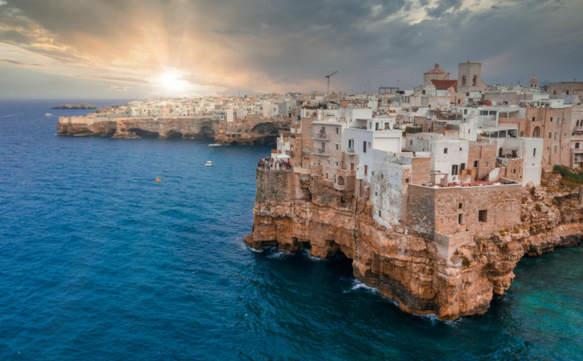 Cityscape of Polignano a Mare surrounded by the sea under the sunlight and a cloudy sky in Italy